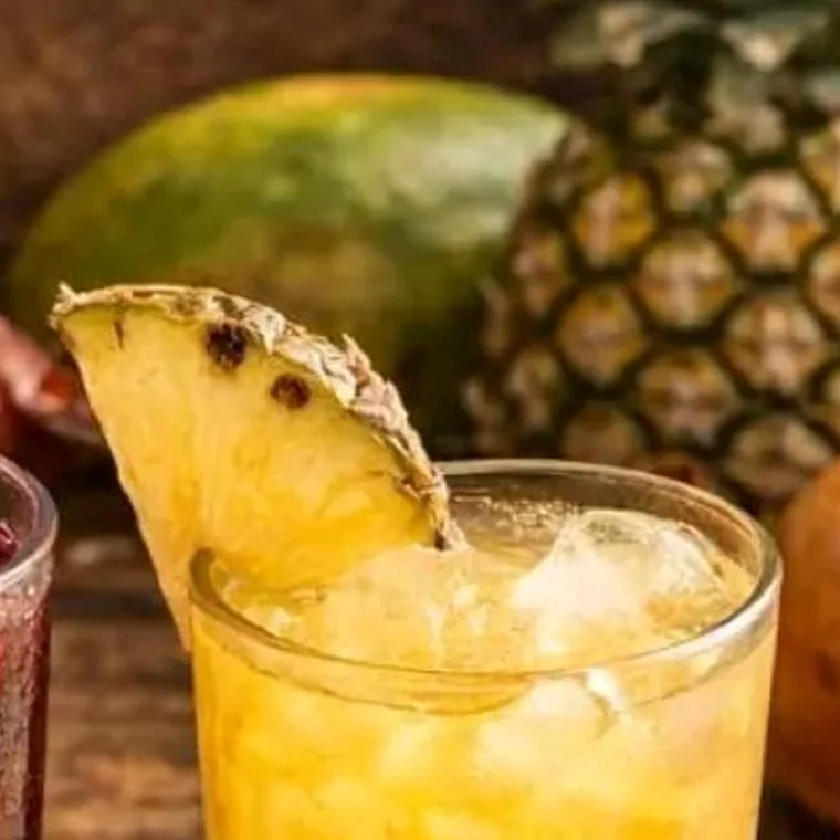 Tranche d'ananas et boisson dorée servie sur glace